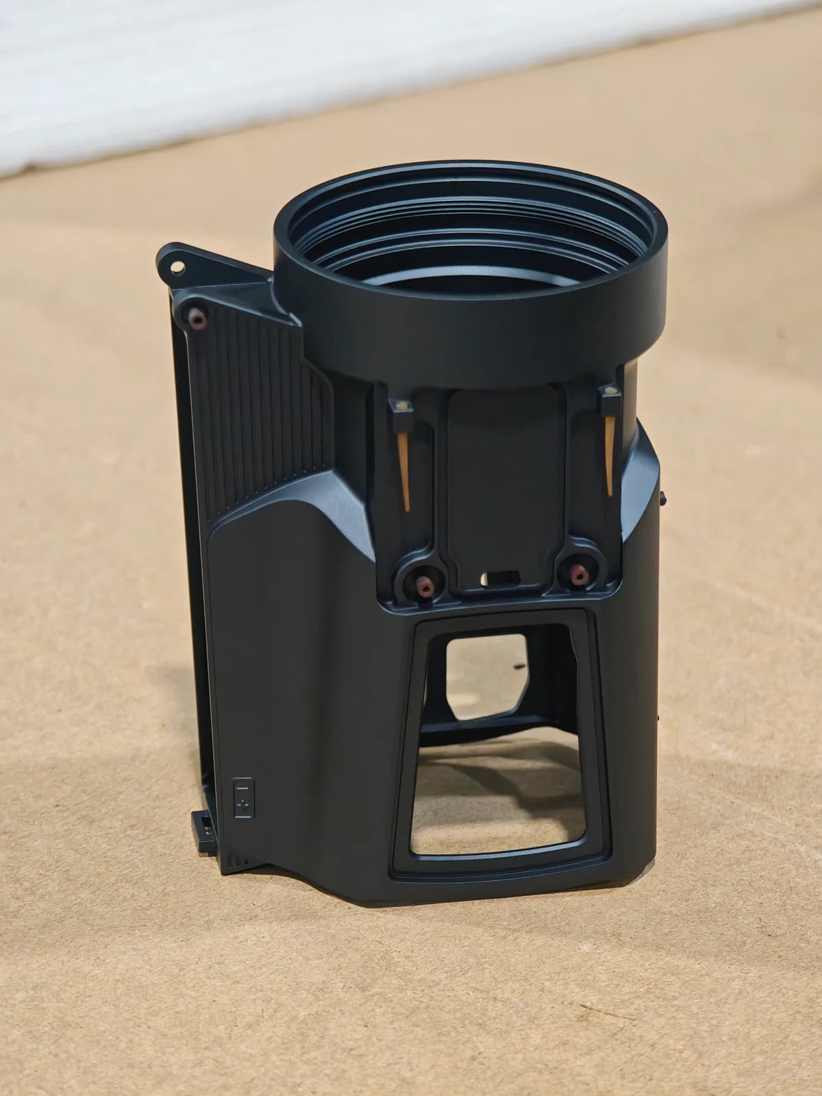 Close-up of a dark metal housing with threaded and machined features.