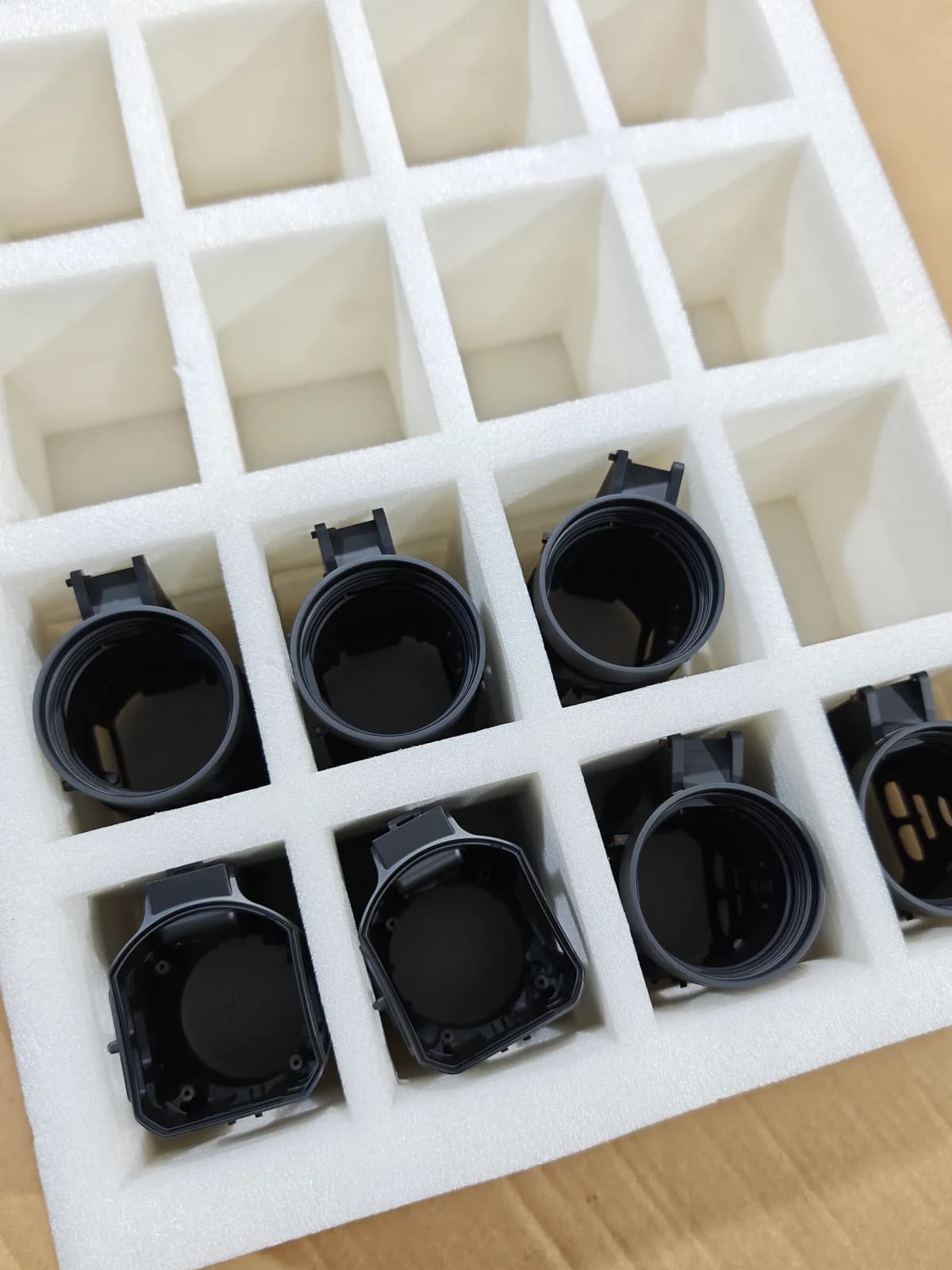 Dark metal housings placed individually in protective foam compartments.