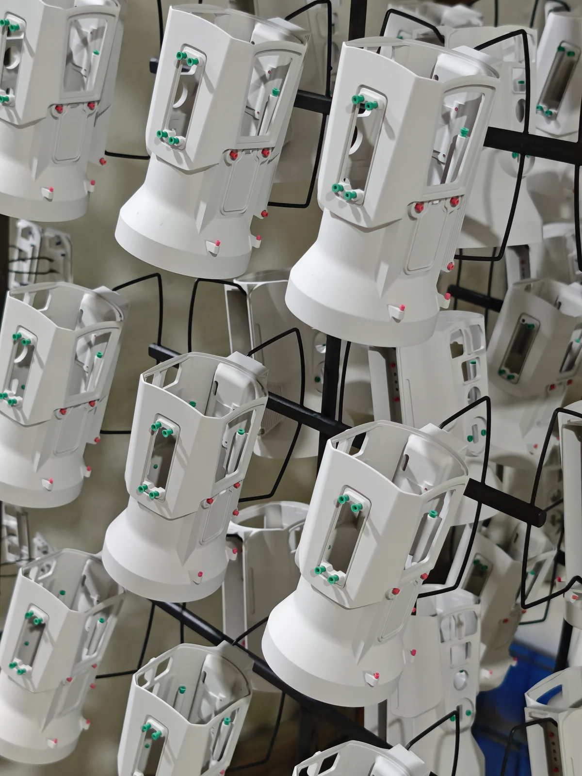 Multiple light-colored metal housings suspended on processing racks.